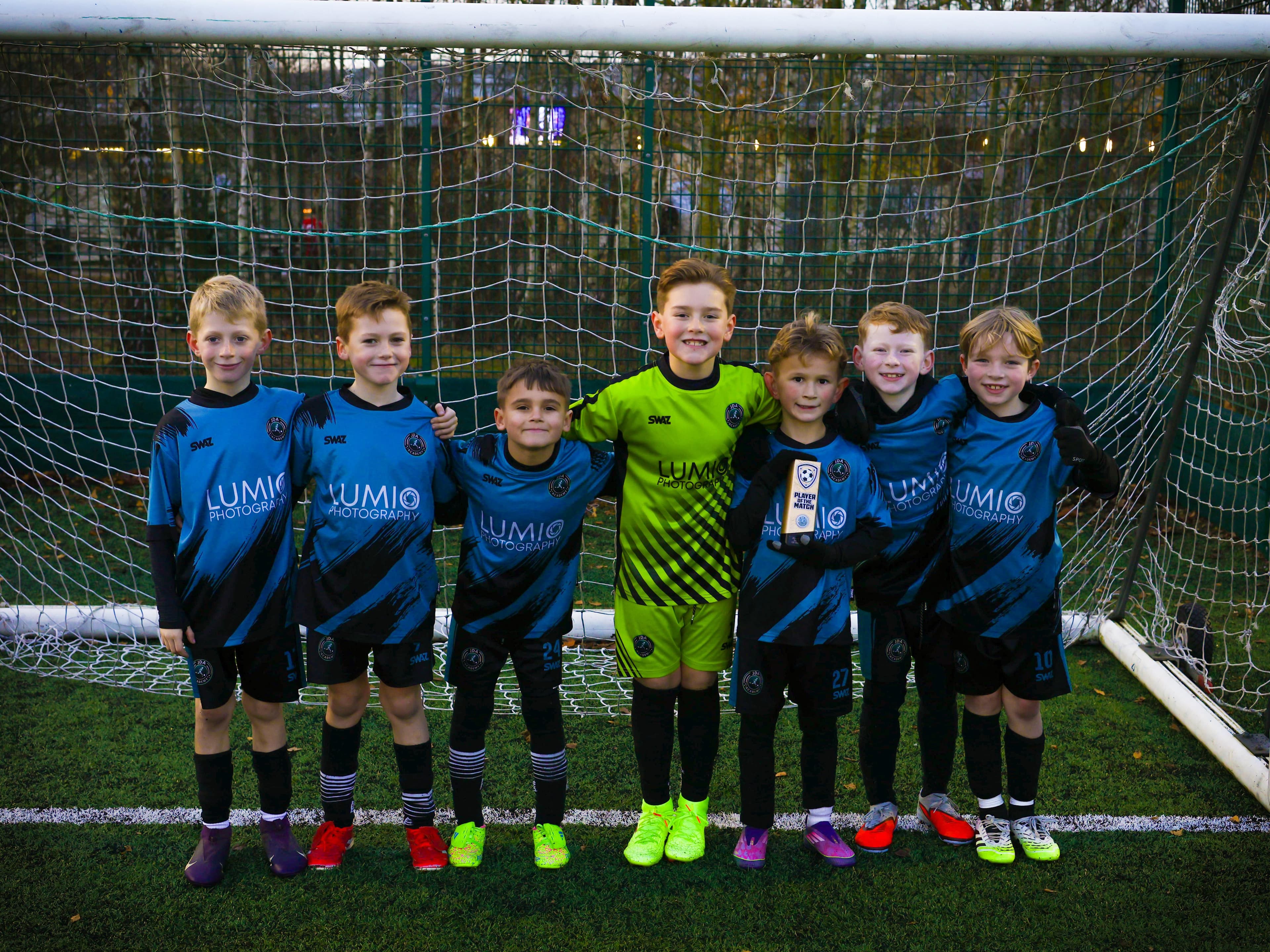 JDA Academy players at a showcase fixture, Lumio Photography branding visible on the kit